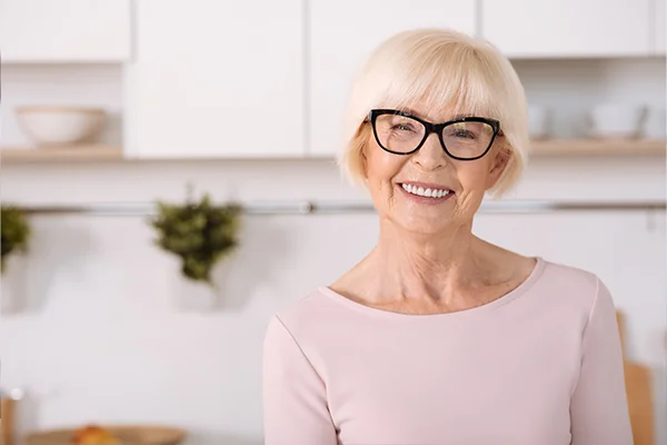 Joyful nice woman standing in the kitchen and smiling with cosmetic dental treatment from Riverwind Dental in Richmond, VA