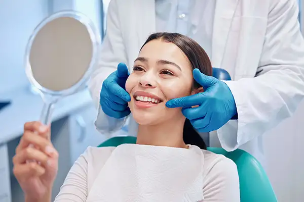 Smiling dental patient looking into mirror after a cleaning at Riverwind Dental in Richmond, VA