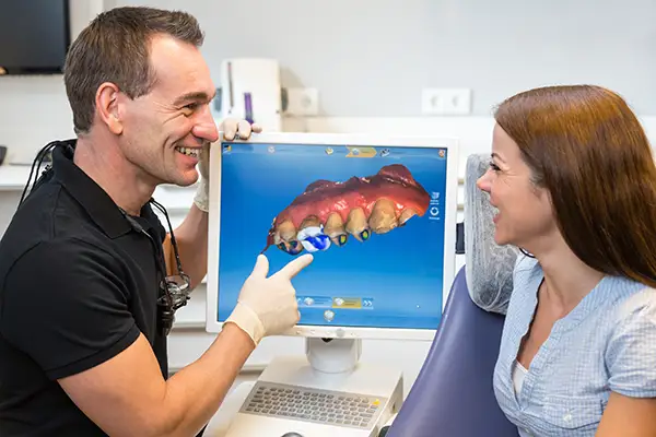 A dentist showing a patient a 3D CAD/CAM dental restoration model on a monitor at Riverwind Dental in Richmond, VA