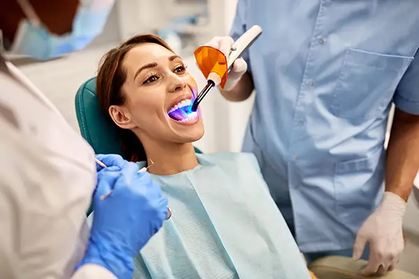 Dentist and assistant performing a dental bonding procedure on a female patient at Riverwind Dental in Richmond, VA